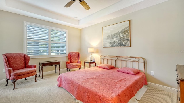 carpeted bedroom featuring a tray ceiling and ceiling fan