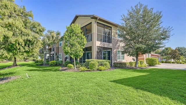 back of property with a sunroom and a yard