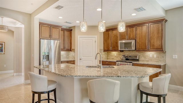 kitchen with decorative light fixtures, a center island with sink, appliances with stainless steel finishes, and sink