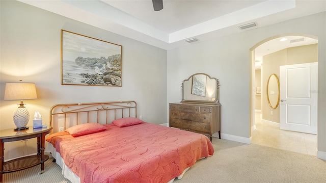 carpeted bedroom featuring ceiling fan and a raised ceiling