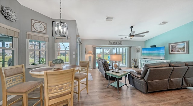 living room with hardwood / wood-style floors, ceiling fan with notable chandelier, and vaulted ceiling