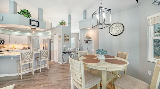 dining space with an inviting chandelier, light wood-type flooring, and a high ceiling