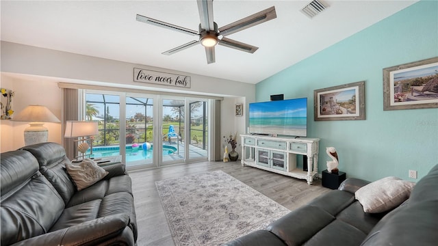 living room featuring light hardwood / wood-style floors, ceiling fan, and vaulted ceiling