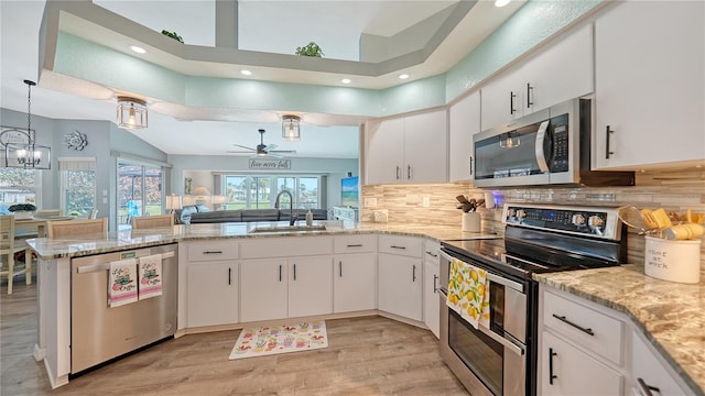 kitchen with kitchen peninsula, sink, pendant lighting, white cabinetry, and appliances with stainless steel finishes