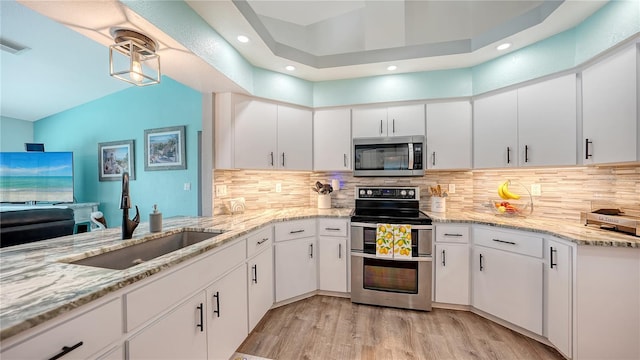 kitchen with sink, appliances with stainless steel finishes, white cabinetry, and light hardwood / wood-style floors