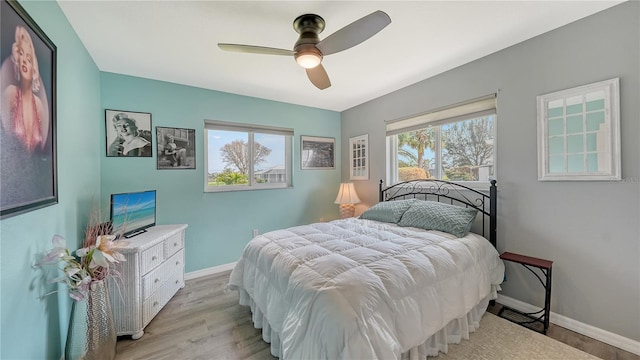 bedroom with ceiling fan, multiple windows, and light wood-type flooring