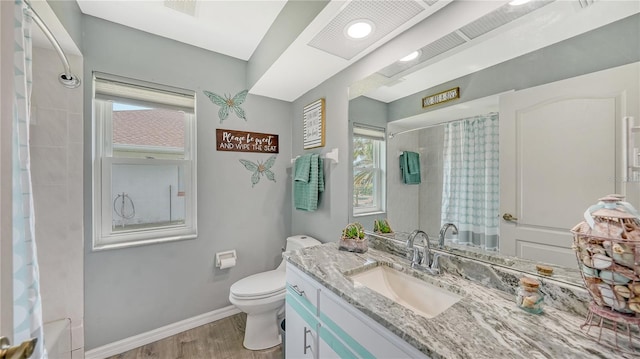 bathroom featuring vanity, toilet, a healthy amount of sunlight, and wood-type flooring