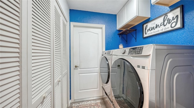 clothes washing area featuring cabinets and washing machine and dryer