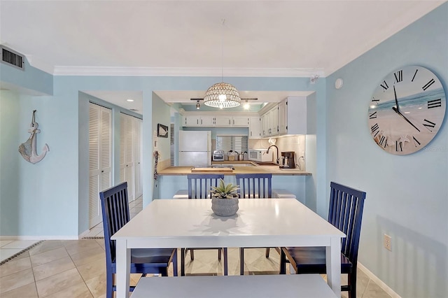 dining room with an inviting chandelier, light tile patterned floors, and ornamental molding