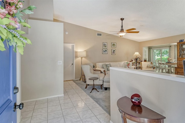 interior space with lofted ceiling, ceiling fan, light tile patterned floors, and a textured ceiling