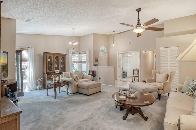 carpeted living room featuring ceiling fan with notable chandelier, a textured ceiling, and a towering ceiling