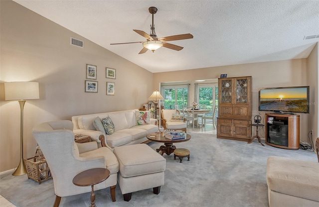 living room featuring a textured ceiling, lofted ceiling, ceiling fan, and carpet floors