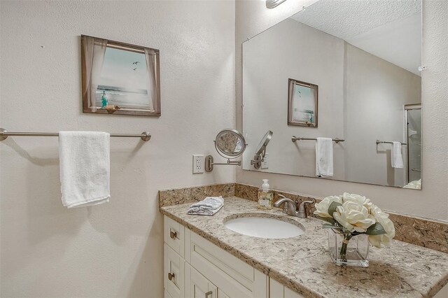 bathroom featuring vanity, vaulted ceiling, and a textured ceiling