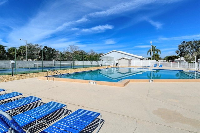 view of swimming pool with a patio and tennis court