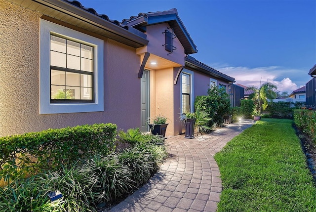 exterior entry at dusk featuring a yard