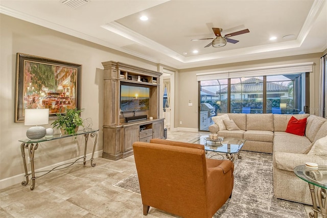 living room with ceiling fan, a tray ceiling, and ornamental molding