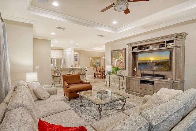 living room featuring ceiling fan, a tray ceiling, and crown molding