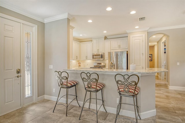 kitchen with kitchen peninsula, a kitchen bar, stainless steel appliances, crown molding, and light stone countertops