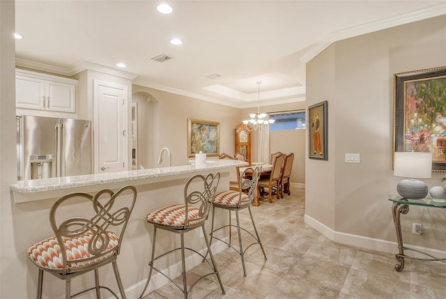 kitchen with light stone counters, decorative light fixtures, a kitchen breakfast bar, a notable chandelier, and high end refrigerator