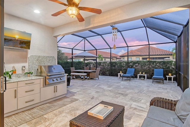 patio terrace at dusk with ceiling fan, area for grilling, and glass enclosure