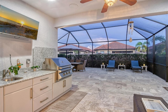 view of patio / terrace featuring ceiling fan, sink, a grill, a lanai, and exterior kitchen