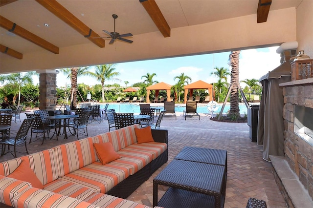 view of patio featuring an outdoor living space with a fireplace, ceiling fan, and a community pool