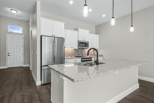 kitchen with pendant lighting, a kitchen island with sink, white cabinetry, appliances with stainless steel finishes, and dark hardwood / wood-style floors