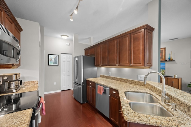 kitchen featuring track lighting, dark hardwood / wood-style floors, sink, stainless steel appliances, and light stone countertops