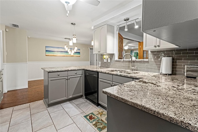 kitchen with gray cabinets, kitchen peninsula, ceiling fan with notable chandelier, and sink