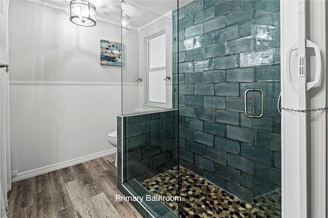 bathroom featuring a shower with shower door, crown molding, hardwood / wood-style floors, and toilet