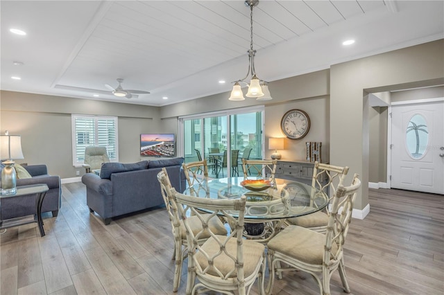 dining space featuring light hardwood / wood-style flooring, a tray ceiling, and ceiling fan with notable chandelier