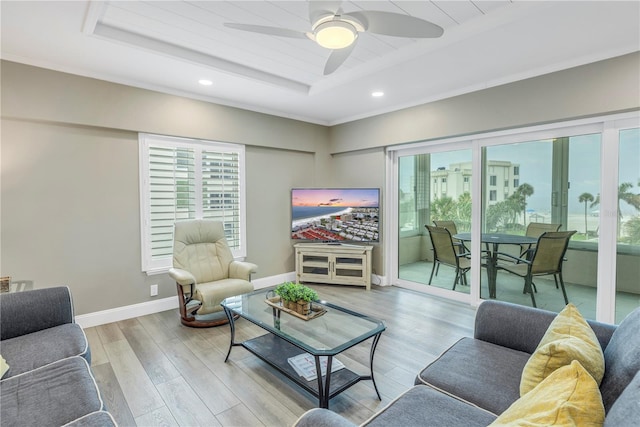 living room featuring a wealth of natural light, a tray ceiling, and ceiling fan