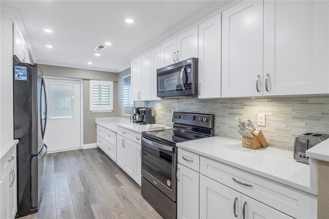 kitchen with black appliances, decorative backsplash, light hardwood / wood-style flooring, and white cabinets