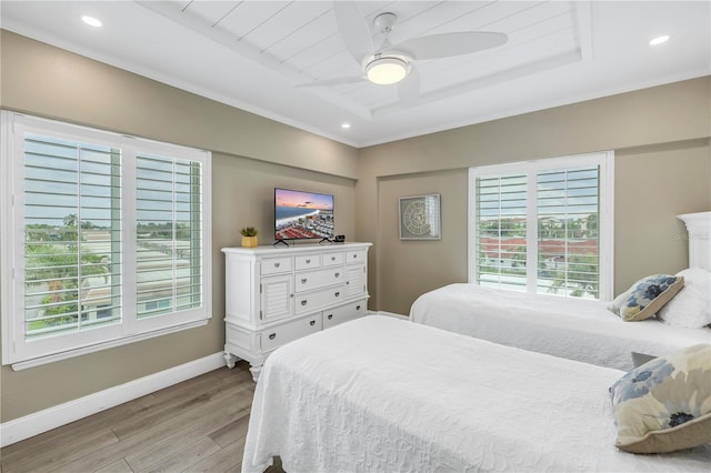 bedroom with ceiling fan, light hardwood / wood-style flooring, and a raised ceiling