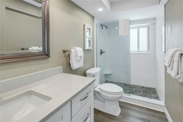 bathroom featuring tiled shower, vanity, toilet, and hardwood / wood-style flooring