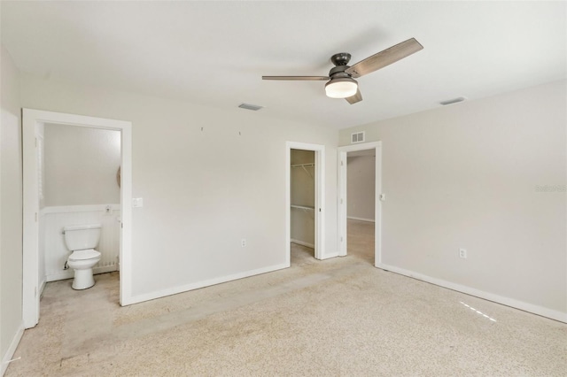 unfurnished bedroom with ceiling fan, a closet, a walk in closet, and ensuite bath