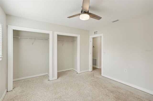 unfurnished bedroom with light colored carpet, ceiling fan, and multiple closets