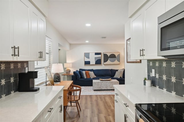 kitchen with light wood-type flooring, white cabinetry, and tasteful backsplash