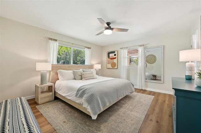 bedroom with ceiling fan, dark hardwood / wood-style flooring, and multiple windows