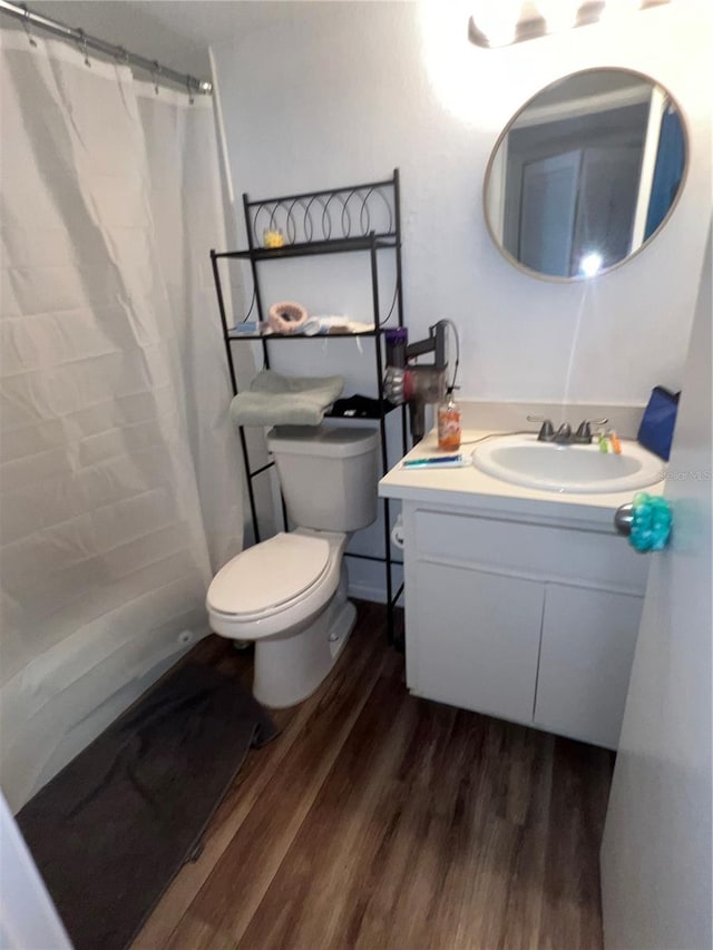 bathroom featuring a shower with shower curtain, wood-type flooring, vanity, and toilet