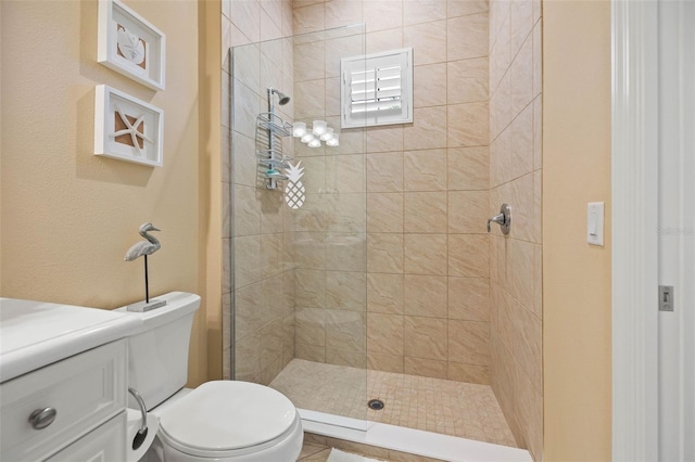 bathroom with a tile shower, vanity, and toilet