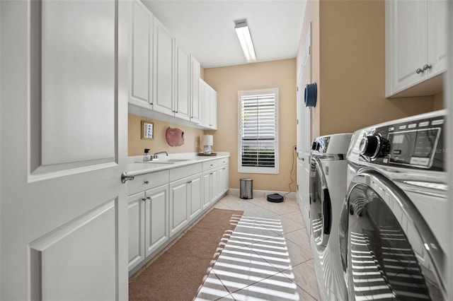 laundry area with light tile patterned floors, sink, washer and dryer, and cabinets