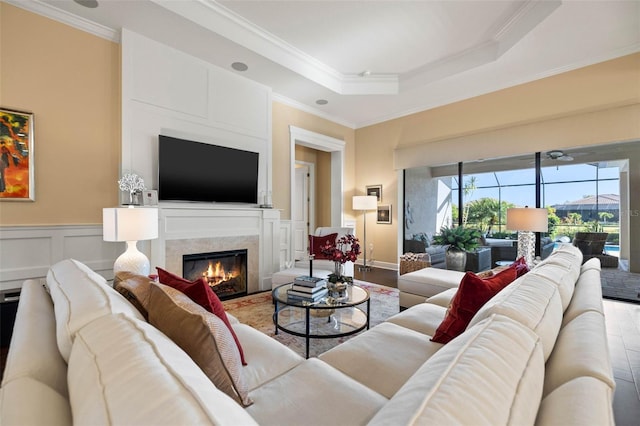 living room with a tray ceiling, hardwood / wood-style flooring, and crown molding