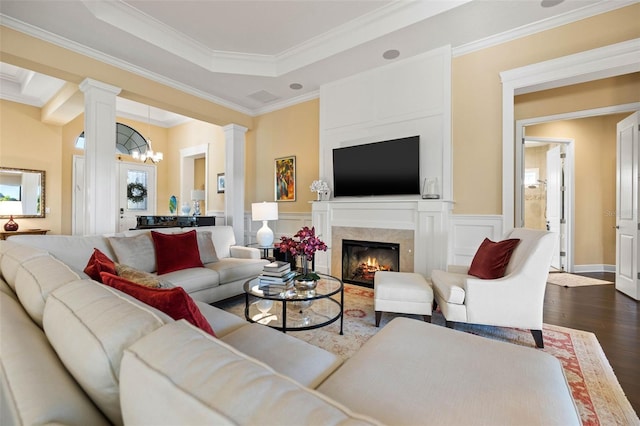 living room with ornate columns, an inviting chandelier, crown molding, and dark hardwood / wood-style flooring