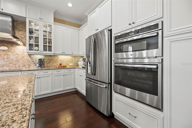 kitchen featuring white cabinets, stainless steel appliances, light stone countertops, crown molding, and dark hardwood / wood-style flooring