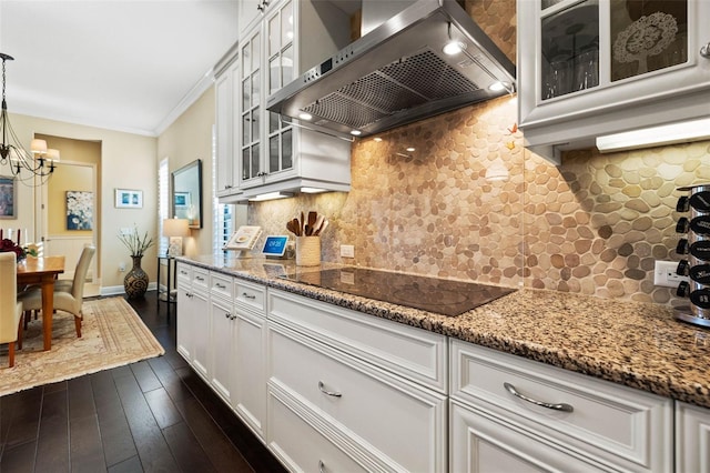 kitchen featuring decorative light fixtures, dark wood-type flooring, wall chimney range hood, white cabinetry, and black electric cooktop