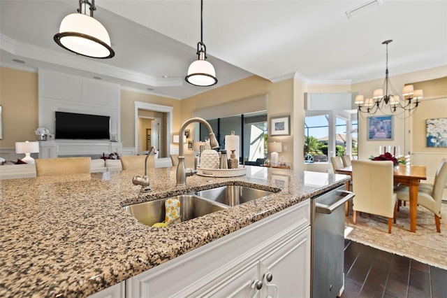 kitchen featuring light stone countertops, hanging light fixtures, dark wood-type flooring, and sink