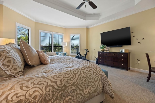 carpeted bedroom with ornamental molding, a tray ceiling, and ceiling fan