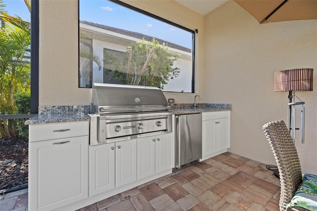 kitchen featuring stainless steel refrigerator, white cabinetry, and light stone countertops