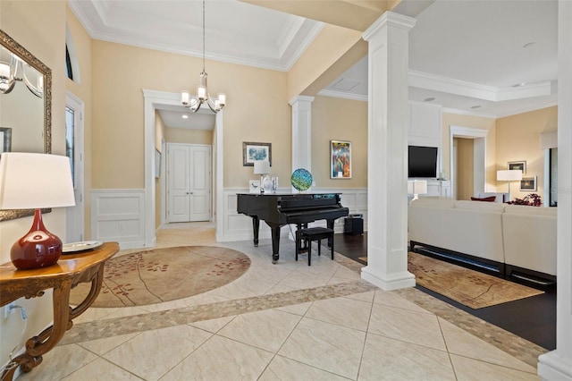 foyer featuring ornamental molding, a notable chandelier, light hardwood / wood-style flooring, and decorative columns